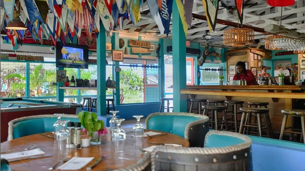Inside the Staniel Cay Yacht Club bar, with burgees and open-air seating looking out to the water